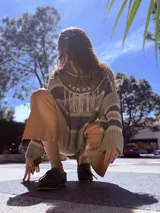 Sweater de tejido de punto de algodón a rayas en tonos verde militar y beige, con cuello de cuero que presenta detalles bordados a mano y flecos frontales.