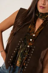 Chaleco marrón de gamuza con cordones laterales y tachas plateadas.