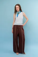 Pantalon de lino color marrón con costuras blancas decorativas a lo largo de las piernas y corte amplio.