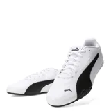 Championes urbanos Puma modelo Catch, color blanco con la icónica franja lateral en negro. Presentan un diseño de perfil bajo con cierre de cordones, puntera redondeada y suela de goma negra con excelente agarre.