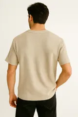 Remera de manga corta en tejido de punto tipo waffle, color blanco, con cuello redondo a la base y bolsillo frontal en el pecho.
