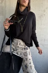 Sweater negro de punto con cuello polera, mangas largas con puños ajustados y diseño holgado.