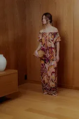 Maxi vestido con estampado floral en tonos naranja, rosa y borgoña, con escote off-shoulder elastizado y mangas cortas con volantes.