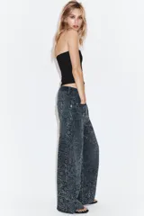 Jeans de tiro medio con corte baggy y cinco bolsillos. Presenta un diseño de estampado floral realizado con aplicaciones de strass a contraste sobre el tejido denim.