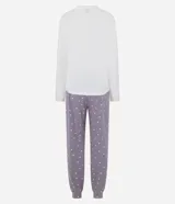 Pijama largo de dos piezas compuesto por una remera de manga larga color blanco con cuello redondo y estampa frontal de un gato con collar de perlas, y un pantalón color lila con estampado de lunares blancos, cintura elástica con cordón y puños ajustados en los tobillos.