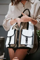 Mochila de cuero color marrón y blanco con cierre de cremallera y dos bolsillos frontales con cierre de hebilla.