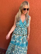 Vestido largo con estampado floral en tonos turquesa y beige, escote en V cruzado y cintura elastizada con cordón ajustable.