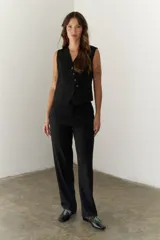 Pantalón negro de corte recto y cintura alta, con bolsillos laterales y cierre.