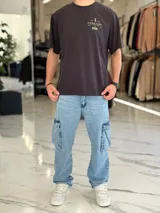 Remera oversize blanca de manga corta, con estampa en la espalda con la inscripción "Concept", un gráfico de pingüino con galera y esferas de líneas.