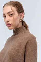 Polera tejida de punto confeccionada en lambswool color gris claro, con cuello alto y calce holgado.