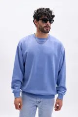 Buzo deportivo de cuello redondo, color azul medio con efecto lavado, de corte holgado y manga larga.