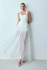 Vestido largo color blanco con cuerpo estructurado de algodón compacto, tirantes anchos, escote cuadrado y falda larga fluida de gasa semitransparente que deja ver unos shorts interiores.