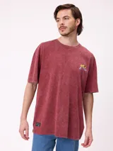 Remera de algodón con calce oversize, color negro con efecto lavado. Presenta un estampado gráfico en la espalda con diseño de espiral en tonos rosado y celeste, acompañado de inscripciones decorativas.