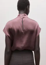 Blusa de seda color rosado oscuro, con cuello alto y diseño recto.