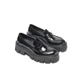 Mocasines de estilo chunky con acabado en charol negro. Presentan una capellada lisa con antifaz clásico, punta redondeada y una plataforma alta de goma con relieve profundo.