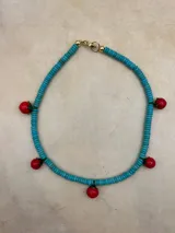 Collar de cuentas turquesas con dijes de tomates rojos.