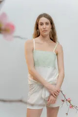 Pijama de dos piezas, compuesto por una musculosa blanca con detalle de puntilla negra elástica en el escote y un short blanco con elástico y lazo negro en la cintura.