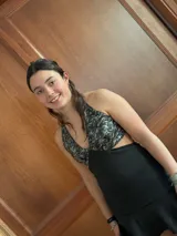 Vestido corto negro con estampado de plumas doradas, escote en V, breteles finos cruzados en la espalda, cut-outs laterales y volado en el ruedo.