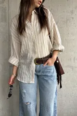 Camisa beige de rayas verticales, de calce relajado y tejido liviano, con mangas largas y cuello camisero.