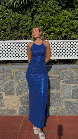 Vestido largo de fiesta azul eléctrico con lentejuelas, corte ajustado, escote halter y abertura lateral en la falda.