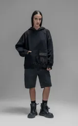 Hoodie oversize color negro, confeccionado en frisa gamuzada de algodón. Presenta capucha forrada en microfibra, mangas raglán y un bolsillo frontal tipo canguro con un bolsillo pequeño superpuesto con solapa.