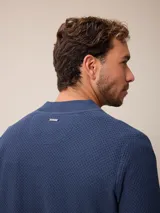 Sweater de punto color negro, con cuello alto y cierre frontal parcial tipo medio cierre. Presenta textura en el tejido y logo bordado en el pecho.