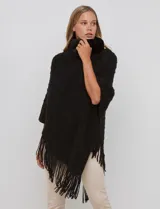 Poncho tejido negro con textura, cuello alto de velour negro y terminación con flecos largos en el ruedo.