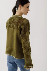 Saco de punto color beige, con diseño de calados en la parte superior y mangas, cierre frontal con botones y cuello redondo.