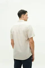 Camisa de manga corta confeccionada en una mezcla de lino y algodón, con cuello clásico, cierre frontal de botones y bolsillo en el pecho con logo bordado.