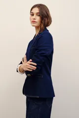Blazer de denim azul oscuro con solapas de muesca, cierre frontal de un botón y bolsillos con solapa.
