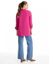 Blusa de tejido piqué color fucsia, con escote en V y pliegue central delantero. Presenta mangas largas con sistema de ajuste mediante presilla y botón, y tajos laterales en el ruedo.