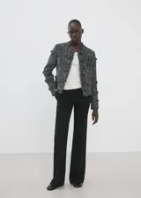 Chaqueta de tweed en tejido jaspeado negro y blanco, con diseño recto, cuello redondo, manga larga y cierre delantero con botones. Presenta terminaciones deshilachadas y detalles de flecos.
