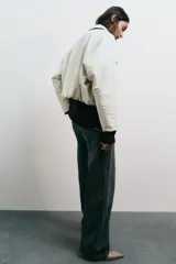 Chaqueta estilo bomber de cuello solapa y manga larga, confeccionada en material efecto piel color beige. Presenta cierre frontal con cremallera, bolsillos delanteros de vivo y bajo con acabado elástico.