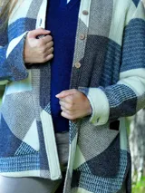 Camisa leñadora de mujer confeccionada en paño de lana con diseño de cuadros patchwork en tonos azul, crudo y marrón, de manga larga y cierre frontal de botones.