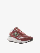 Championes New Balance modelo 9060, con diseño inspirado en la estética tecnológica del año 2000. Presenta una combinación de colores en tonos rojizos, con detalles en verde y blanco. Cuenta con mediasuela ergonómica con amortiguación ABZORB y SBS, y barras estabilizadoras ampliadas.