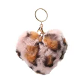 Llavero con dije en forma de corazón de peluche sintético con estampado animal print en tonos rosado, marrón y negro. Incluye argolla y gancho metálico dorado.