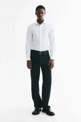 Camisa de algodón blanca con cuello italiano, cierre frontal de botones y mangas largas con puños ajustables. Corte entallado Slim Fit.
