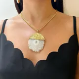 Collar con cadena de eslabones dorados y dije de piedra semipreciosa, posiblemente ágata, de forma semicircular. La parte superior del dije tiene un acabado metálico dorado martillado, mientras que la inferior es de piedra azul oscuro con vetas.