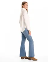 Buzo de tejido suave con cuello volcado ajustable mediante cordones con punteras metálicas. Presenta mangas largas con puños decorados con botones metálicos, hombros caídos y ruedo redondeado con aberturas laterales.