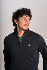 Buzo de cuello alto con cierre frontal parcial, manga larga y puños acanalados. Presenta un diseño liso en color negro con el logo de la marca bordado en el pecho.