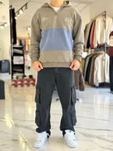 Hoodie de felpa con capucha y medio cierre frontal, diseño en bloques de color celeste y blanco, con bordados decorativos en el pecho.