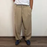 Pantalón sastrero color beige, de corte baggy, con pliegues en la cintura y bolsillos laterales.
