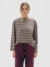 Remera de manga larga con calce holgado, confeccionada en algodón. Presenta un diseño a rayas horizontales en tonos beige y negro, con bordado de letras SP en el pecho y estampa de la marca en la manga.