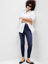 Jean tipo legging de tiro alto en color azul oscuro con lavado uniforme. Presenta un corte ajustado que se ciñe a la figura desde la cintura hasta el tobillo, con cierre frontal de botón y cremallera.