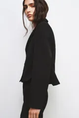 Blazer corta negra de la colección Zara Woman, con cuello solapa de muescas y manga larga. Presenta detalles de pespuntes marcados y forro interior a tono. Cierre frontal con botones.