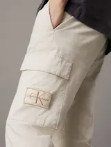 Pantalón cargo Calvin Klein Essentials de algodón ripstop elástico color beige claro, con corte skinny, cintura elástica, puños elásticos y bolsillos cargo con solapa.