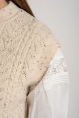 Chaleco de punto con textura trenzada, color beige melange, de cuello redondo y corte al cuerpo.