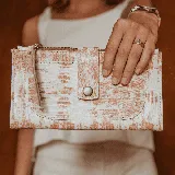 Billetera de cuero con estampado jaspeado en tonos beige y rosa. Tiene bolsillo frontal con broche, dos bolsillos con cierre en los extremos y dos bolsillos para tarjetas en el interior.