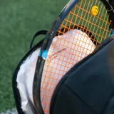 Mochila deportiva negra de diseño minimalista, con múltiples compartimentos, incluyendo espacio térmico para raquetas, bolsillo inferior ventilado para calzado y compartimento interno para laptop.