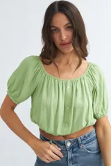 Blusa verde claro con escote off-shoulder, mangas cortas abullonadas con elástico y corte crop.